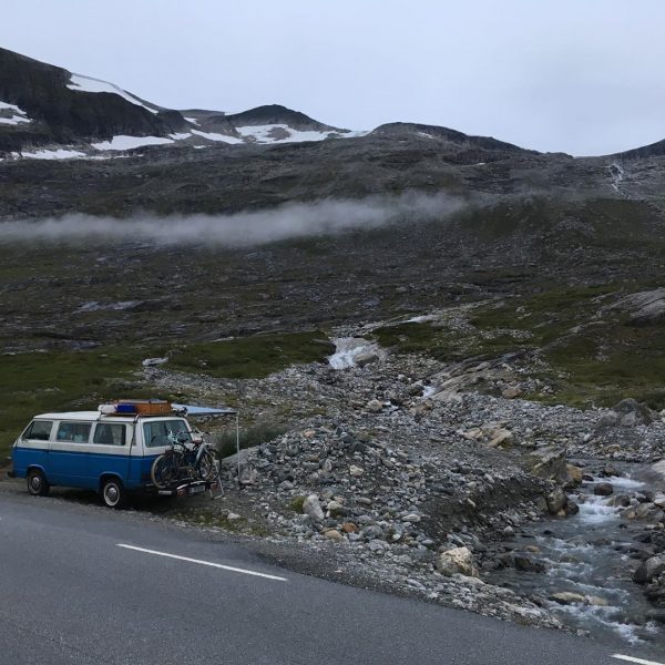 Ein alter VW-Bus steht mit aufgekurbeltem Vordach vor einem Geröllfeld.