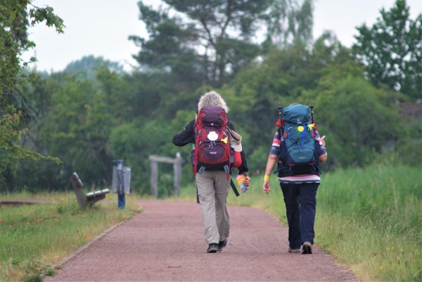 Zwei Wanderer auf einem Weg am Fluss entlang.
