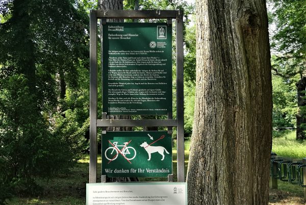 Ein Verbotsschild in einem Park weist daraufhin, dass Hunde an der Leine geführt werden müssen.