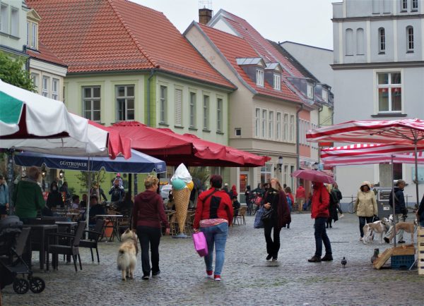 Menschen gehen über den Marktplatz von Greifswald.
