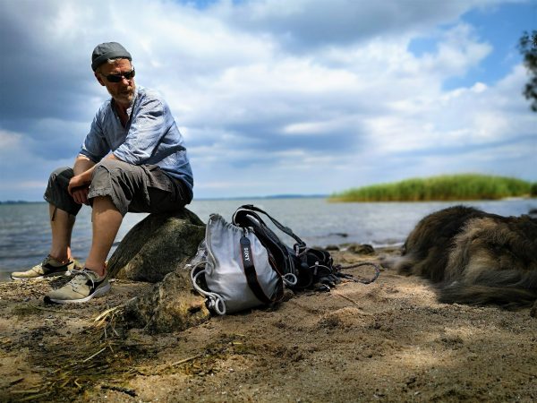 Ein Mann und sein Hund rasten in einer kleinen Badebucht.