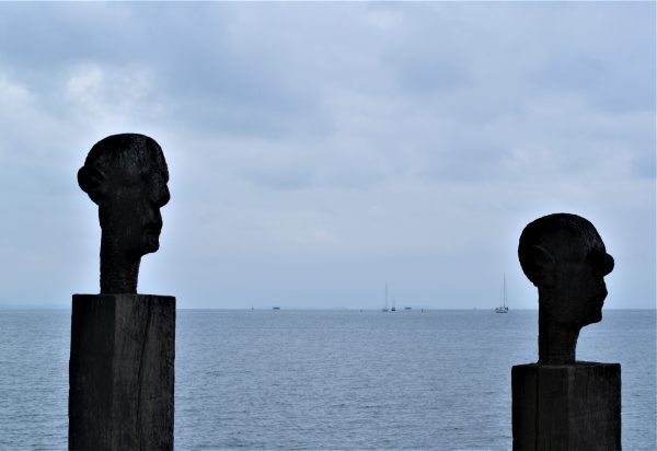 Zwei aus Holz geschnitzte Männerköpfe stehen auf Säulen am Greifswalder Bodden.
