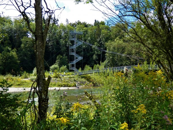 Ein Brücke spannt sich über einen seichten Fluss, die Iller.