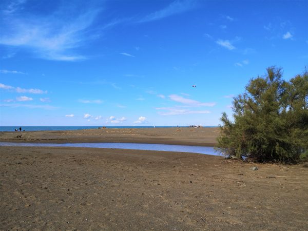 Ein Fluss mündet in einen Strand in der Toskana.