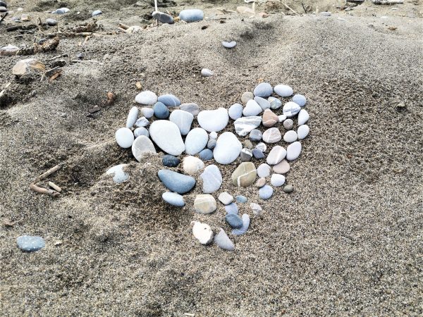 Ein Herz, aus Steinen geformt, liegt am Strand.
